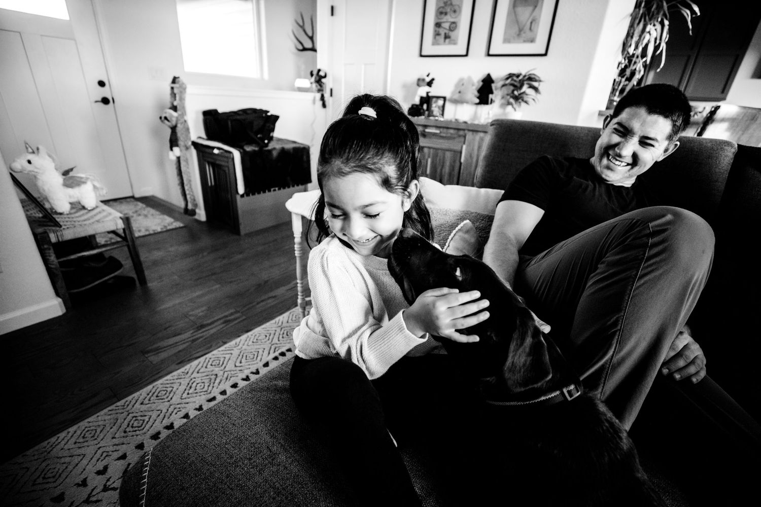 Little girl with dog licking her face and dad smiling in the background in Dickson, TN