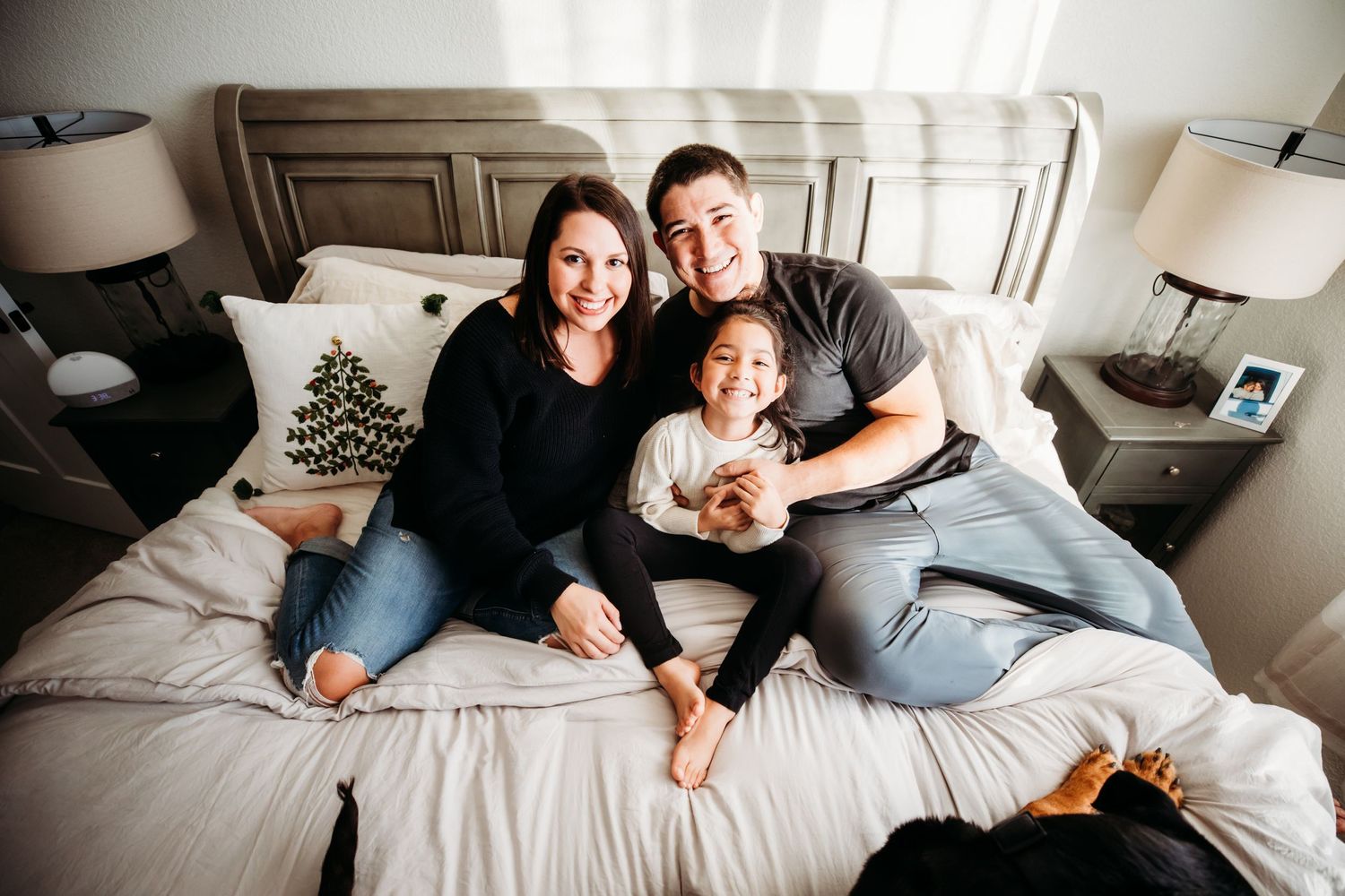 Mom, dad, and little girl sitting together at home on the bed in Dickson, TN