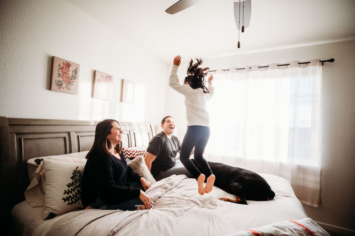 Mom, Dad, and little girl on bed during family session. Little girl bouncing on the bed in Dickson, TN