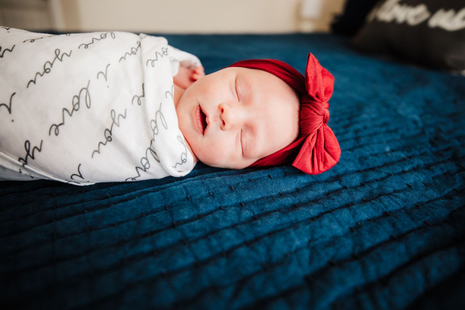 Newborn baby with red bow on her head laying on blue blanket in Dickson, TN