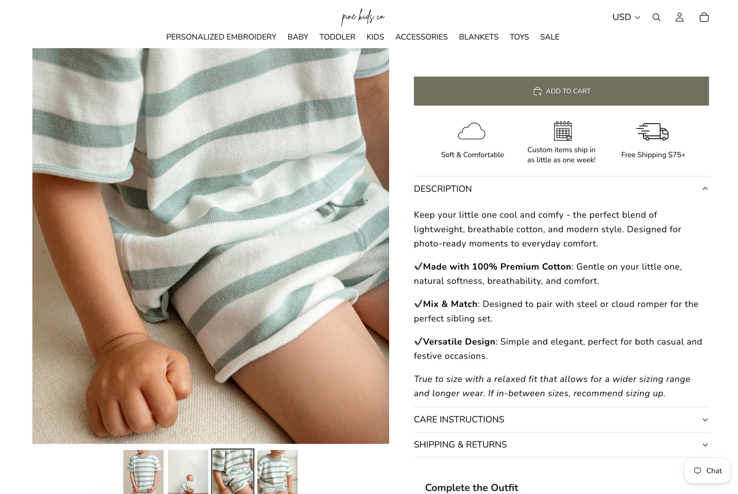 Baby boy wearing a light blue striped short sleeve shirt and white shorts, sitting on a white surface.
