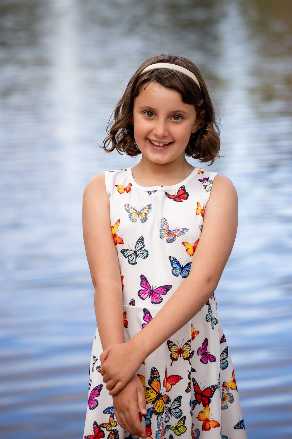 A girl smiles in front of a lake during golden hour