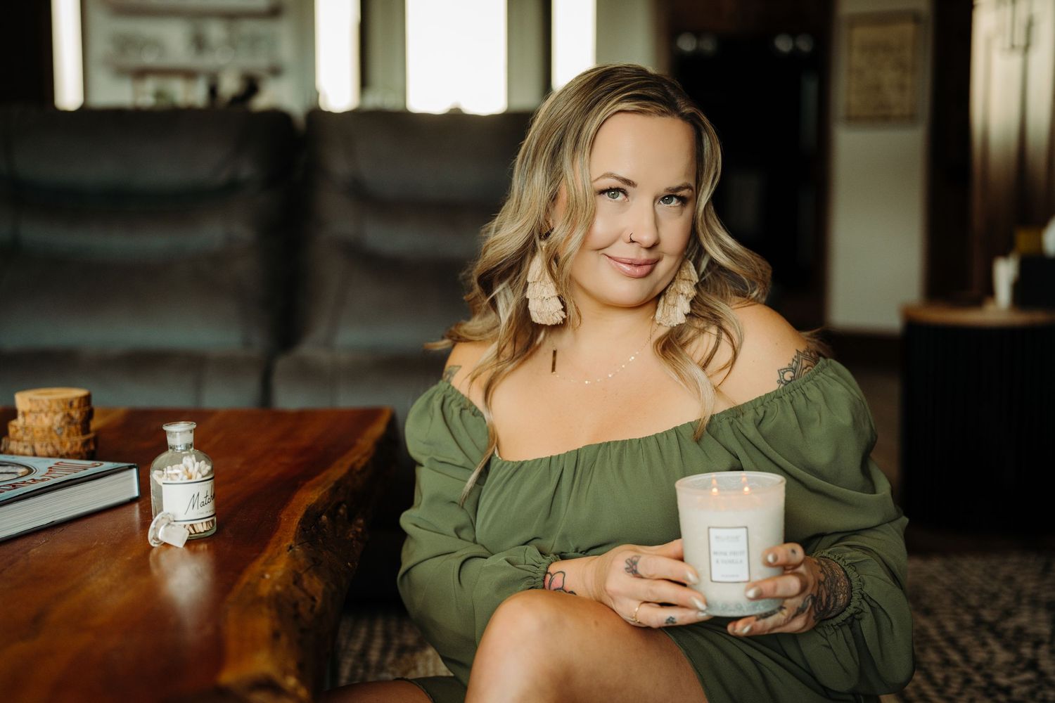 Woman sitting on floor holding Starbucks cup beside wooden coffee table in cozy modern living room.