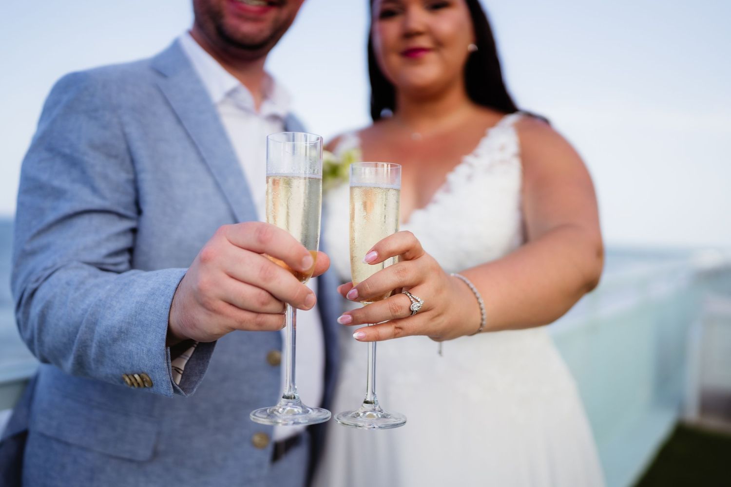 Bride and groom toasting with champagne flutes at their wedding celebration outdoors.