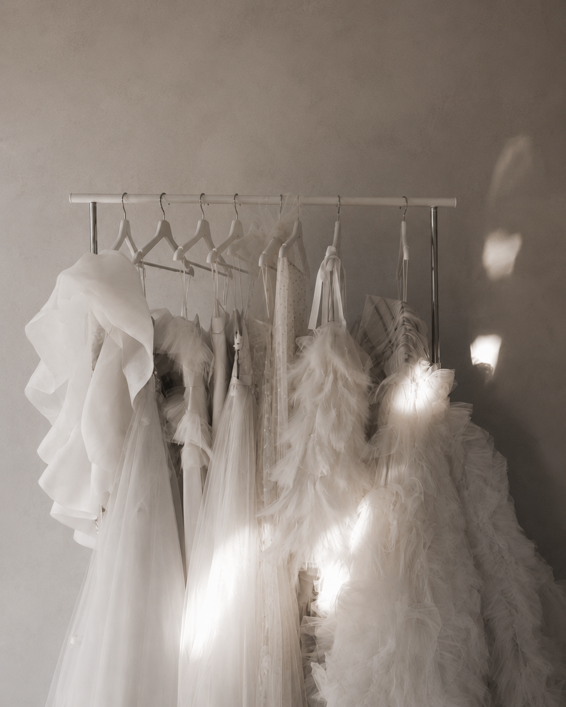 Row of bridal and bridesmaid gowns hanging on a rail.