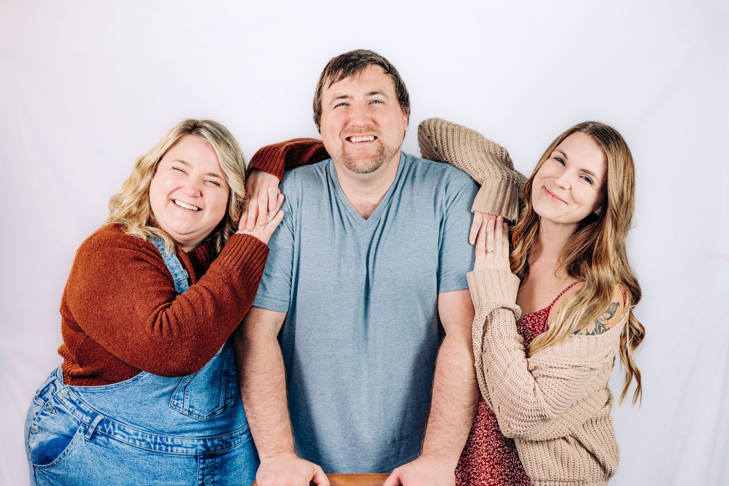 Three smiling people pose together against a white background in a casual family portrait photo.
