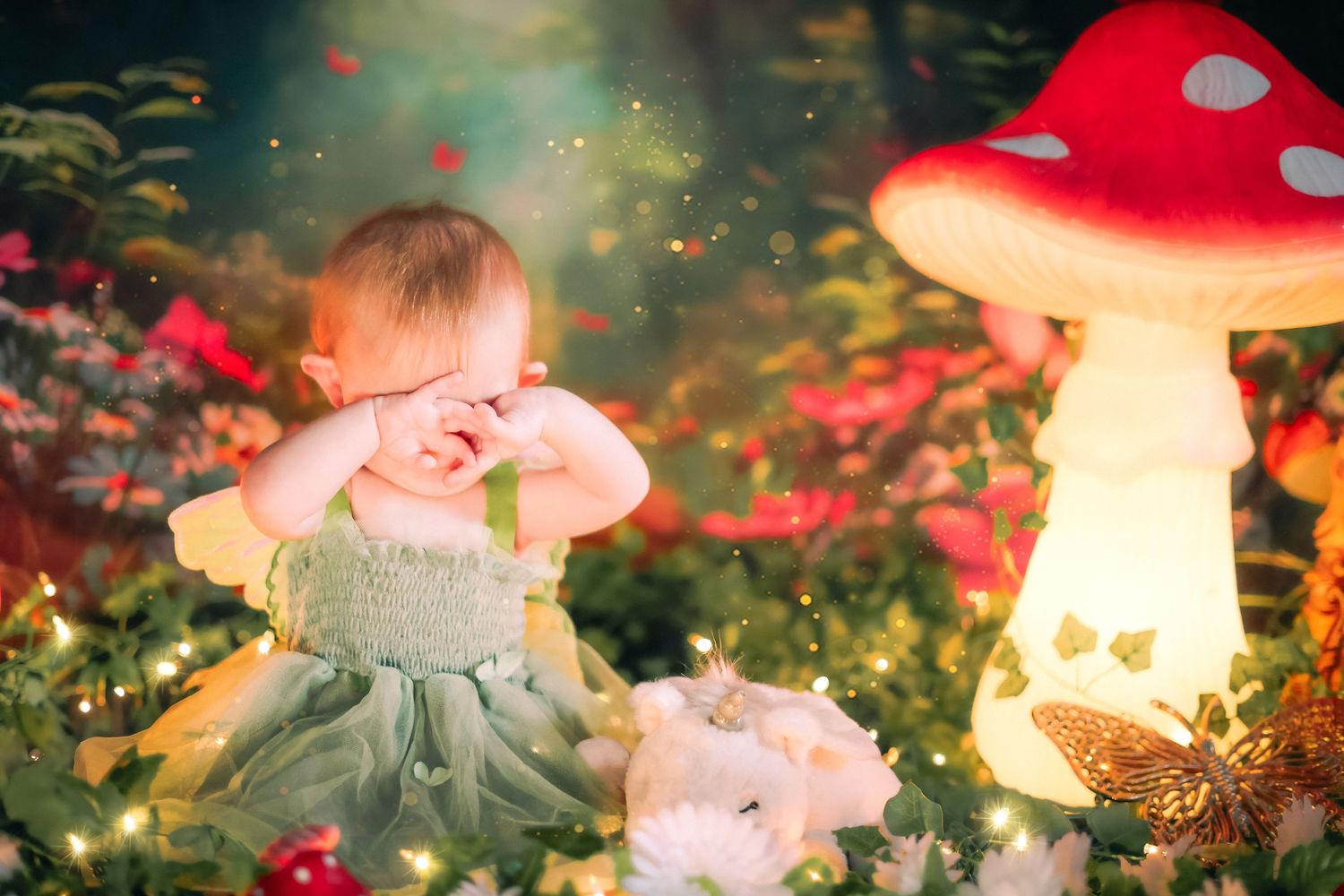 Baby girl in green dress crying in enchanted fairy garden with glowing mushrooms and twinkling lights a home session in Lake Worth, FL.
