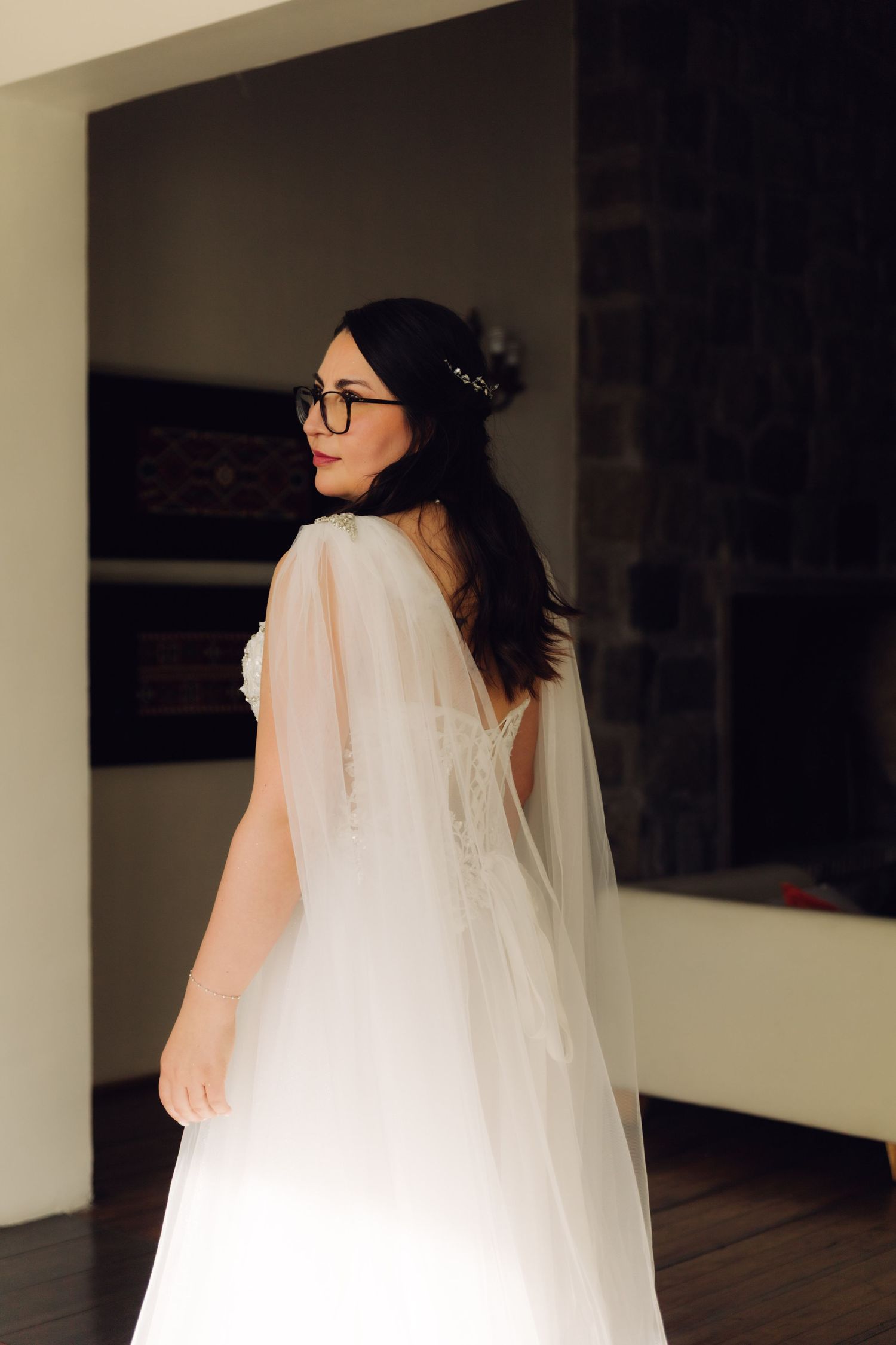 Bride in white tulle wedding gown with cape veil turns gracefully showing back detail.