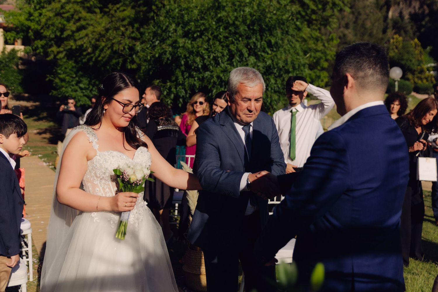 Father presents bride to groom during outdoor wedding ceremony.