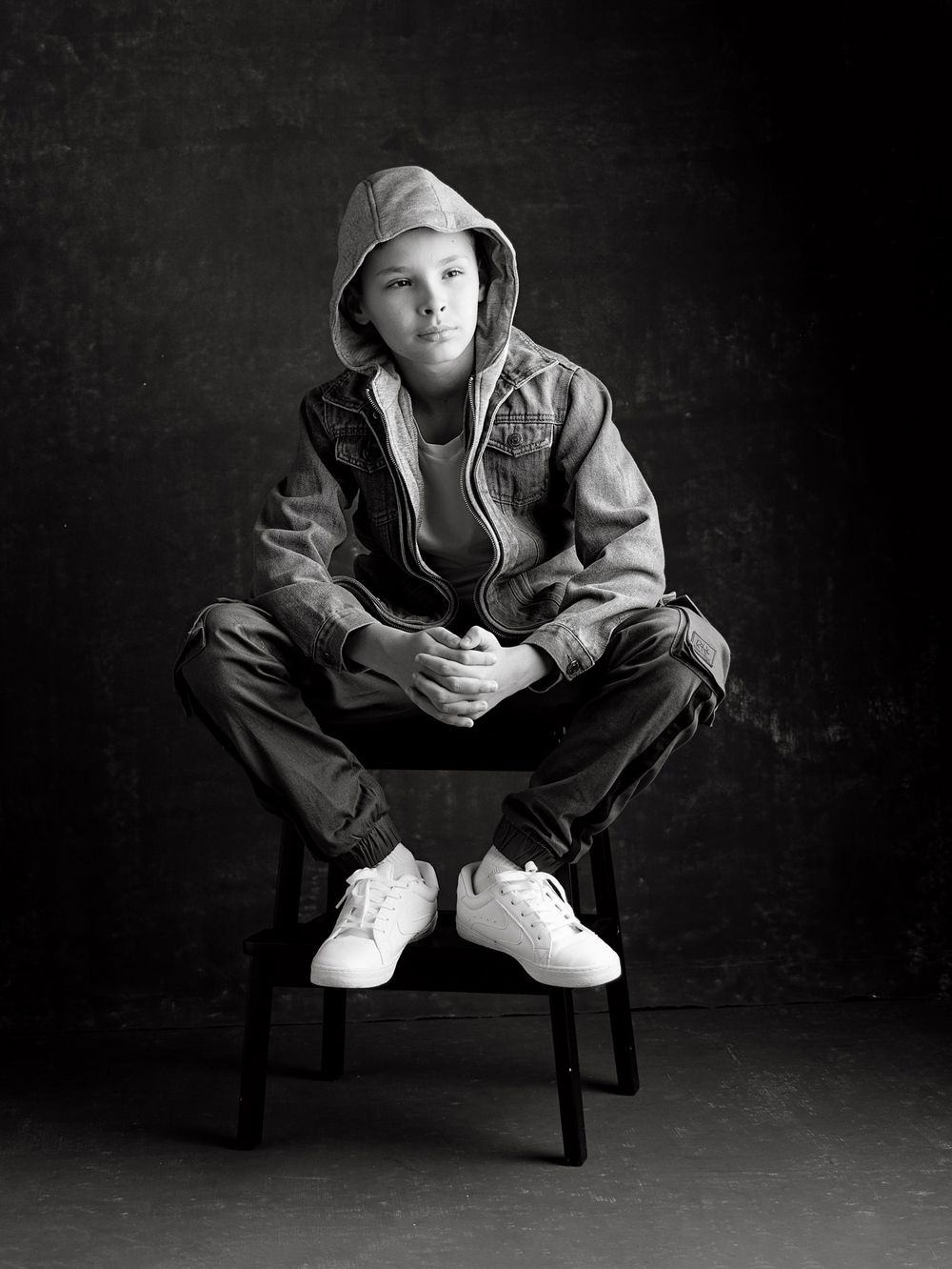 Black and white portrait of a confident boy wearing a denim jacket with a hood during a modern back-to-school photoshoot in Atlanta.