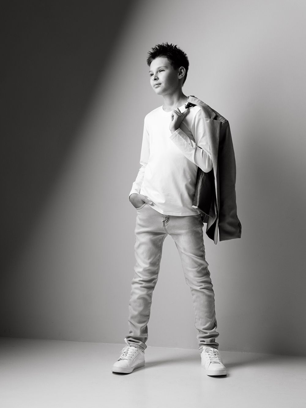 Confident portrait of a school-age boy standing with a blazer over his shoulder before the new school year.