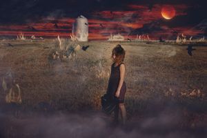 Young girl in a dark dress stands in a field beneath a red moon and stormy sky as crows fly near a distant stone tower.