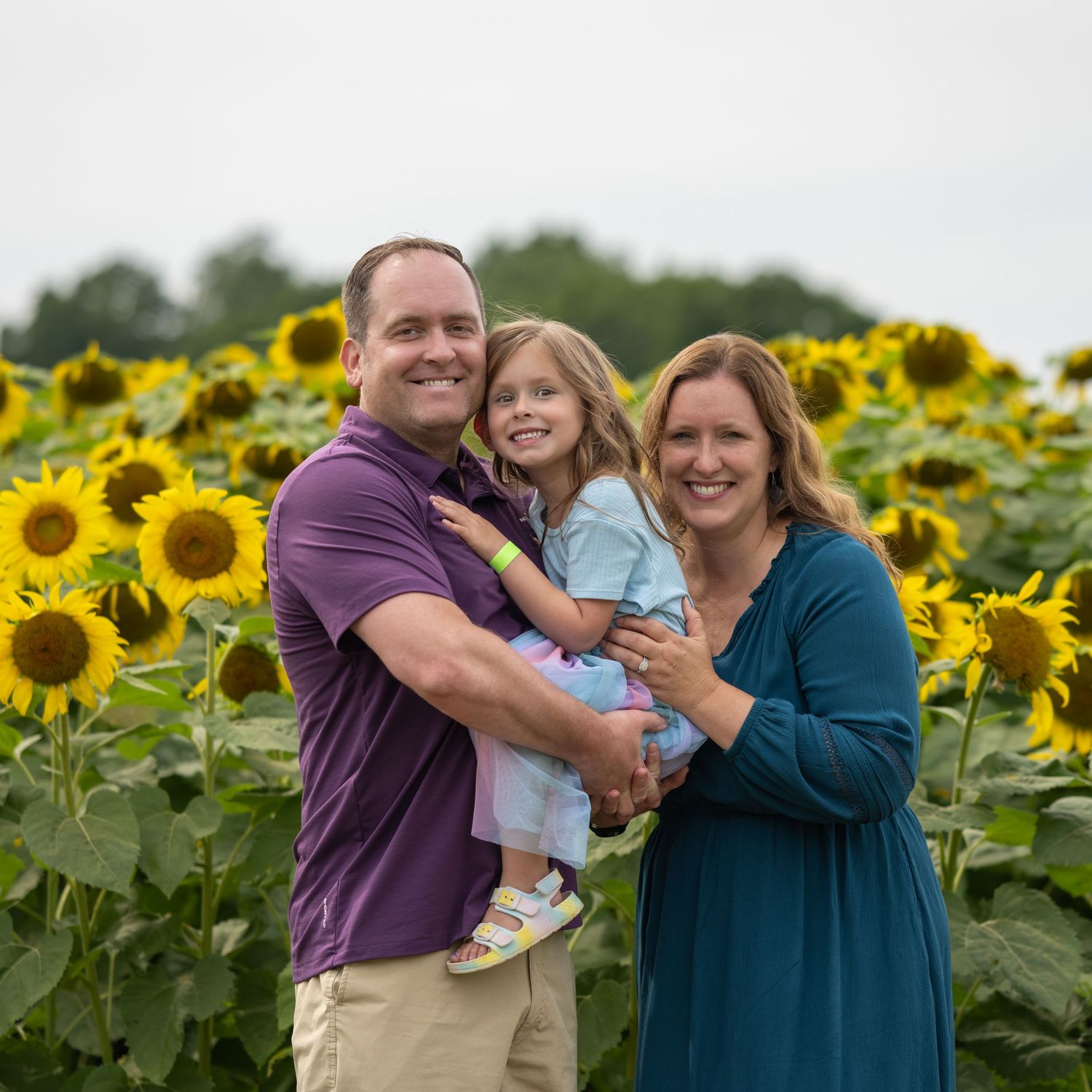 Family of three smiling in a New Hampshire Sunflower Mini Session Photography Session