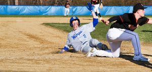 Baseball players slide into bases during a competitive game on a dusty diamond field.