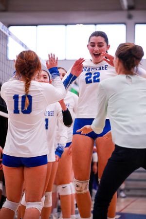Volleyball team members celebrate together in their blue and white uniforms during a match.