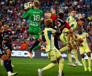 Intense soccer match action between teams in yellow and dark uniforms near the goal.