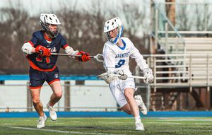 Lacrosse players from opposing teams compete for ball possession during an intense match.