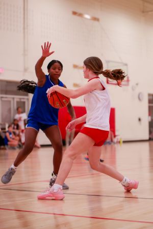 Two players from opposing teams engage in a dynamic basketball play on the court.
