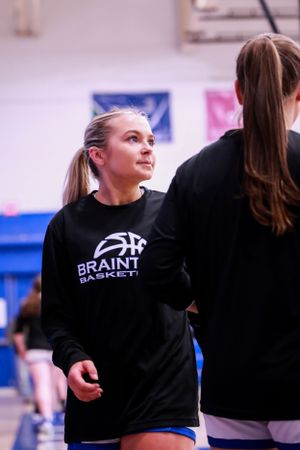 Basketball team members wear black sweatshirts during practice or game.