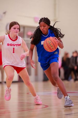 Two players from opposing teams race down the court during a fast-paced basketball game.