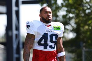 New England Patriots player in practice jersey stands on field during training camp.