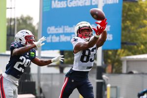 Two football players compete for a catch during a practice session.
