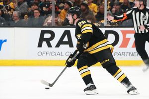 NHL players from the Bruins and Oilers compete for puck possession during gameplay.