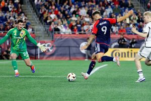 Soccer players in action with goalkeeper defending the goal during match.