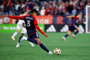 Soccer players battle for control of the ball on a well-lit professional pitch.