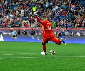 A goalkeeper makes a dramatic diving save during a professional soccer match.