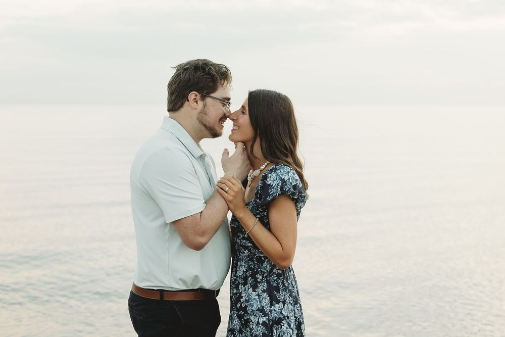 Romantic couple holding hands and sharing a tender moment by the ocean at dusk.
