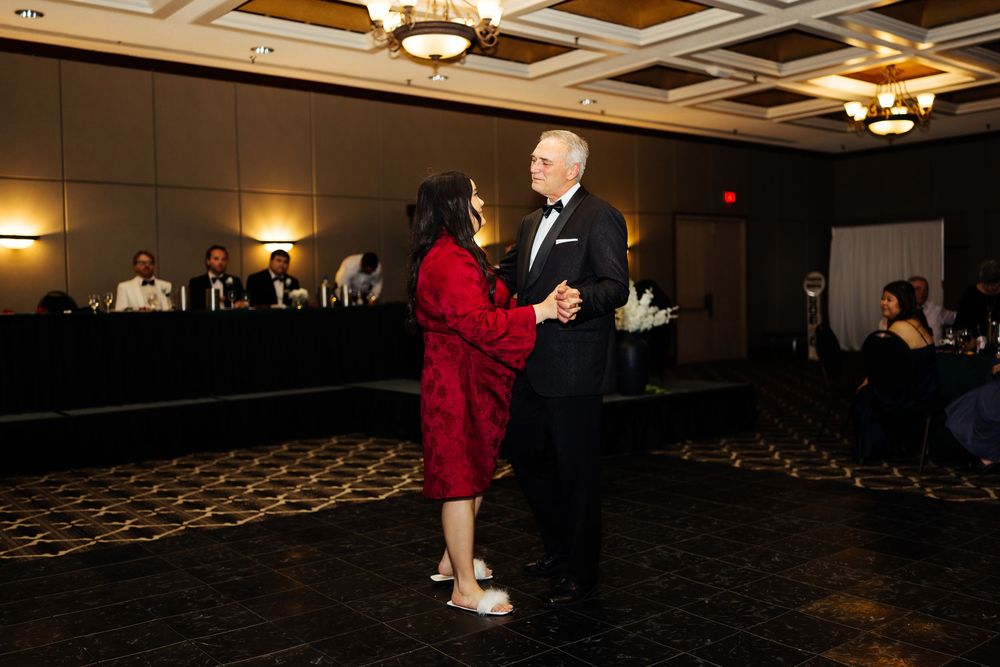 Couple dancing elegantly in a ballroom at a formal event, man in tuxedo and woman in red dress.