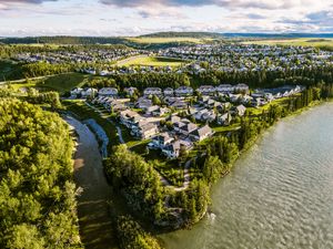 Aerial view of a suburban neighborhood nestled beside a river, surrounded by green trees and open fields.