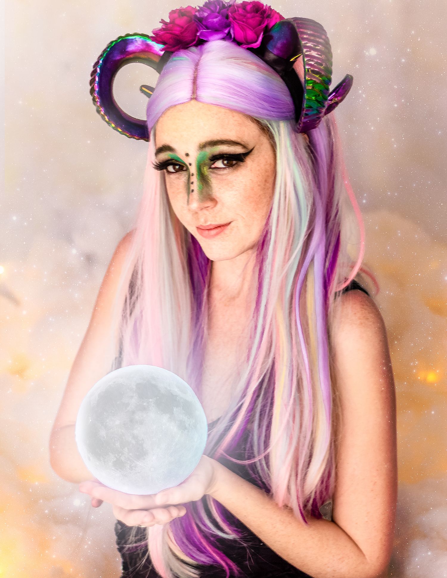 Woman in fantasy costume with rainbow wig, ram horns, floral crown, green makeup, holding glowing moon orb a creative portrait.