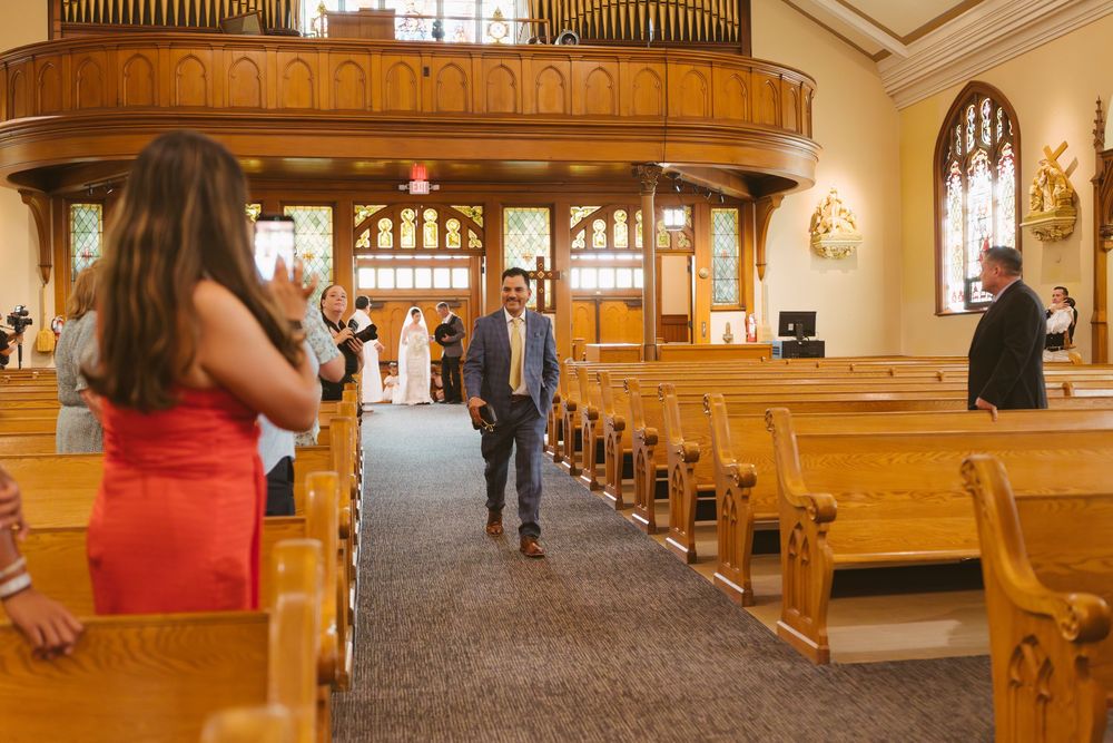 Guests walking down the aisle of a wooden church during a wedding ceremony.