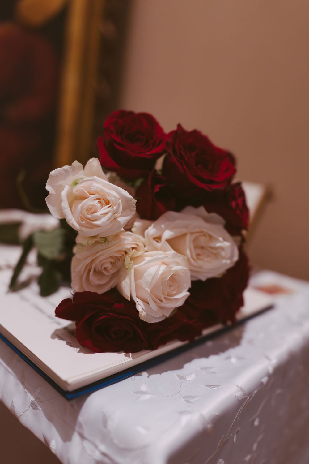 Elegant bouquet of red and white roses resting on a book at a wedding reception.