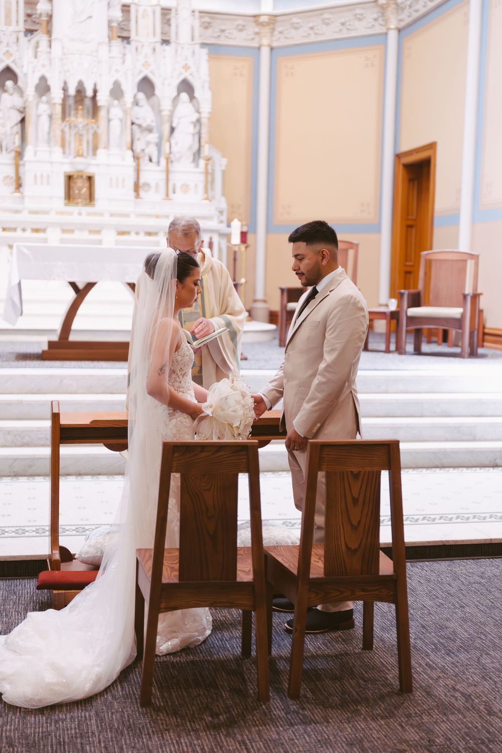Bride and groom exchange vows at altar during elegant Catholic church wedding ceremony.