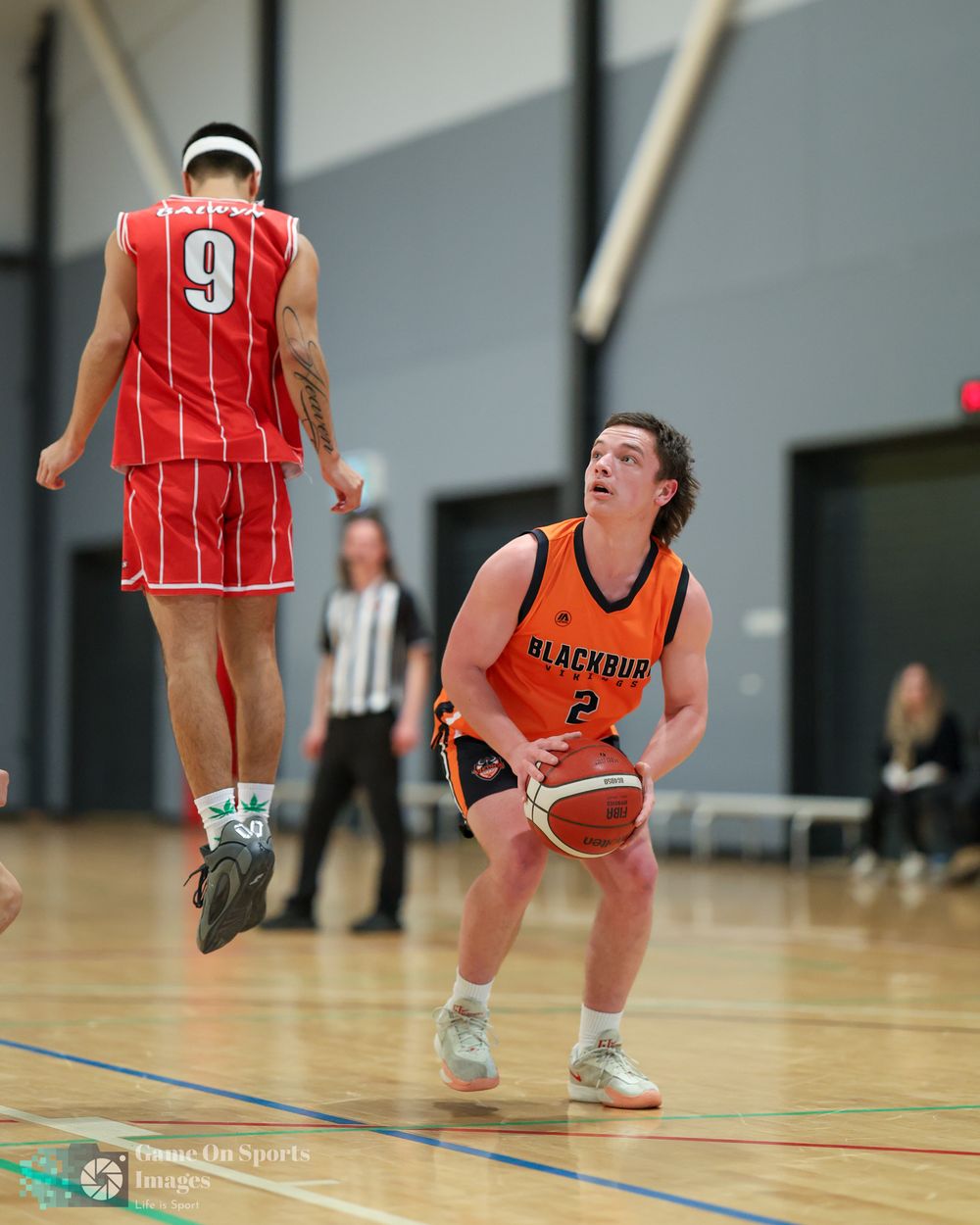Blackburn player #2 prepares to shoot while opponent #9 jumps during an indoor basketball game.