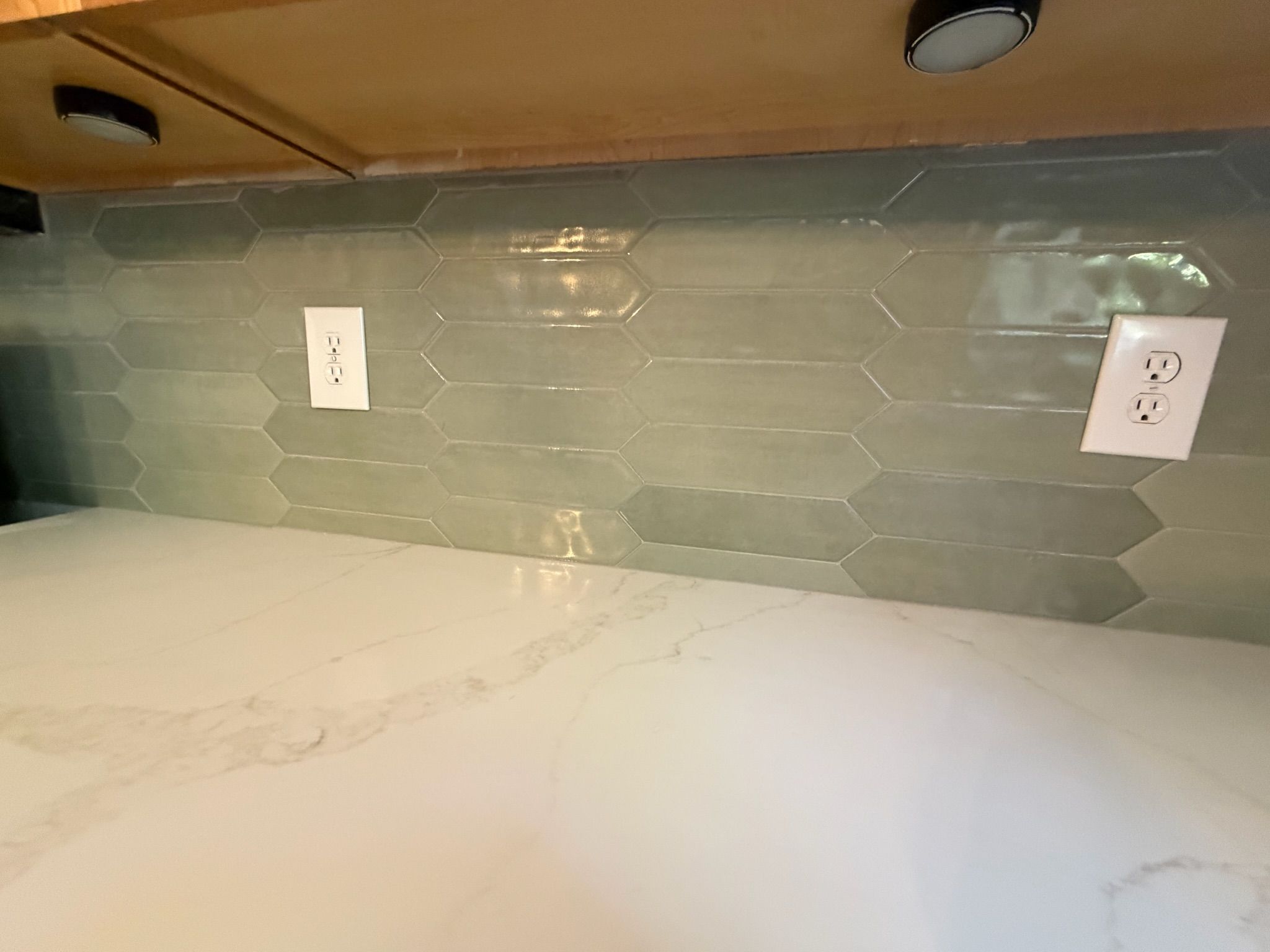 Soft sage green elongated picket glass tile backsplash with white marble quartz countertop in a modern kitchen.