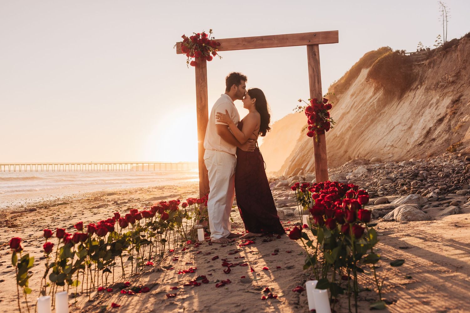 A romantic couple embracing and laughing together on a sunny beach.