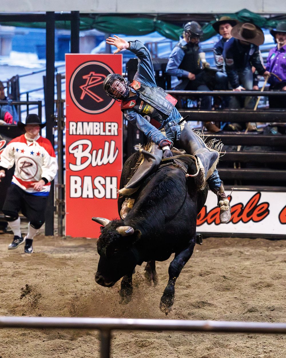 Bull rider in blue gear atop black bull at the Rambler Bull Bash rodeo.