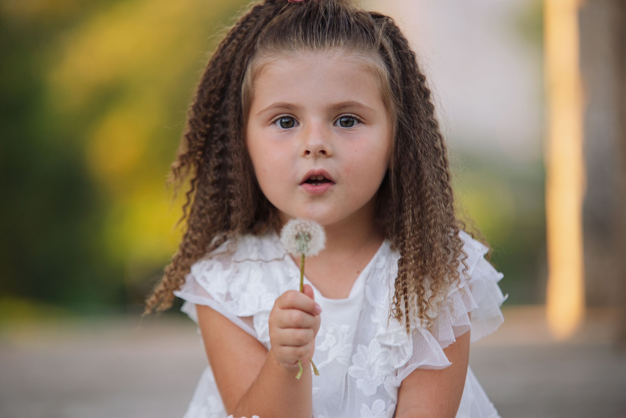 Bambina con soffione durante un ritratto all’aperto