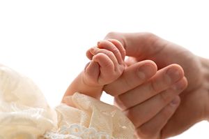 A newborn baby's tiny hand gently gripping an adult's finger, symbolizing new life and parental bond.