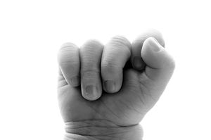 Close-up black and white photo of a clenched human fist showing knuckles and fingers curled inward.