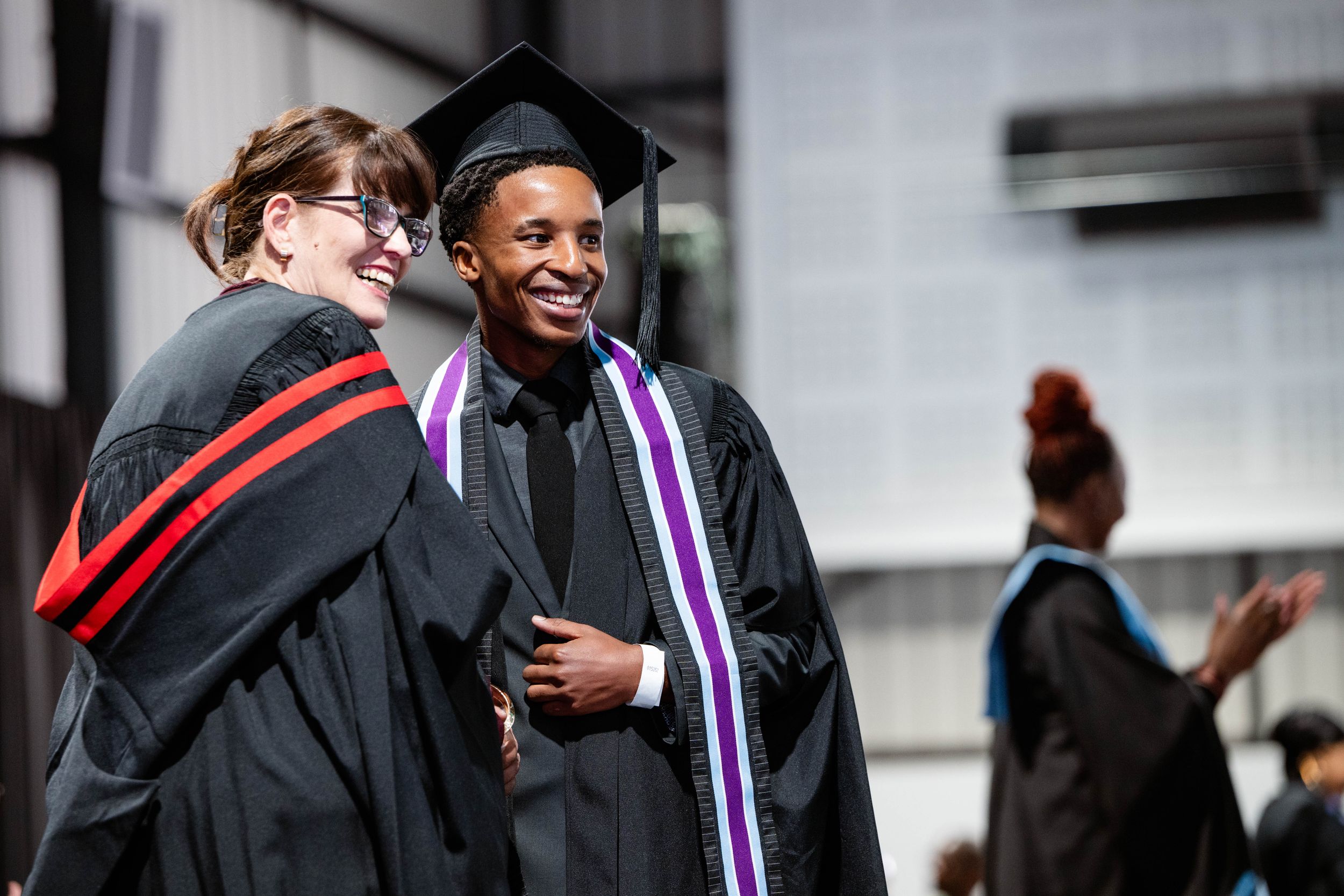 Happy graduate sharing a celebratory moment on stage at the Emeris Sandton Campus graduation.