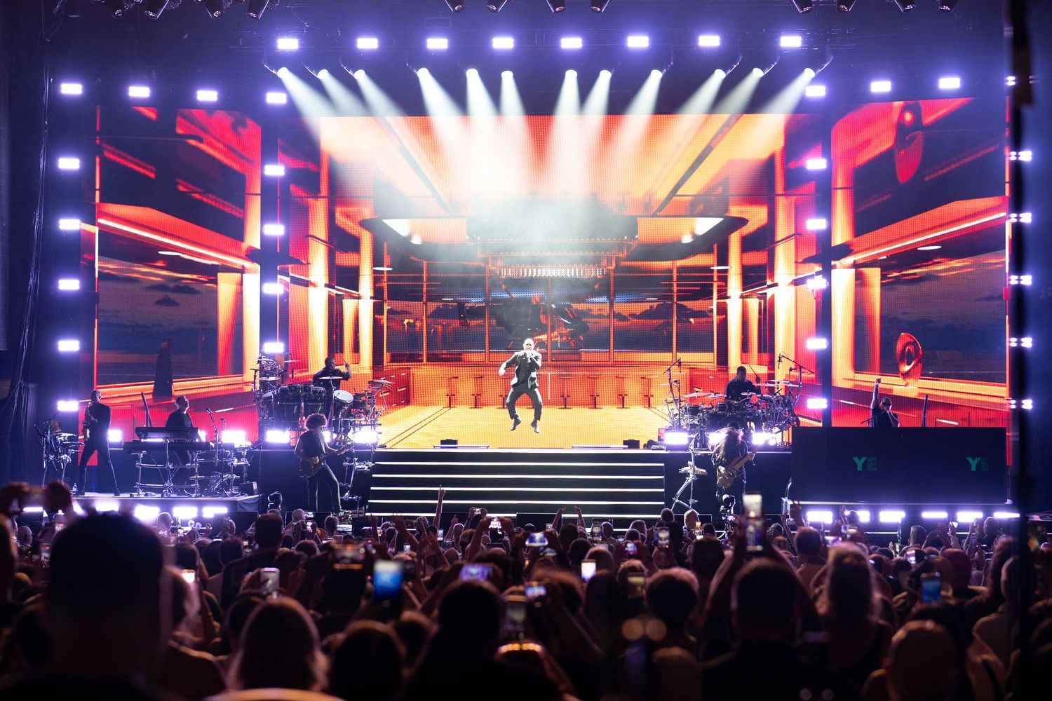 A vibrant concert stage with bright LED lights, performers, and an energetic crowd enjoying a live music show.