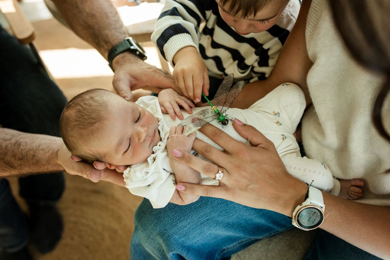 Parents and sibling cuddling newborn baby during an in-home lifestyle newborn photography session in Calgary