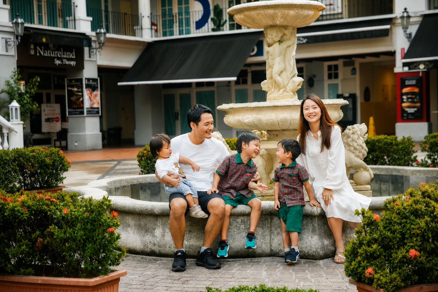 Cheerful family of five sharing a fun moment together by an ornate stone fountain.