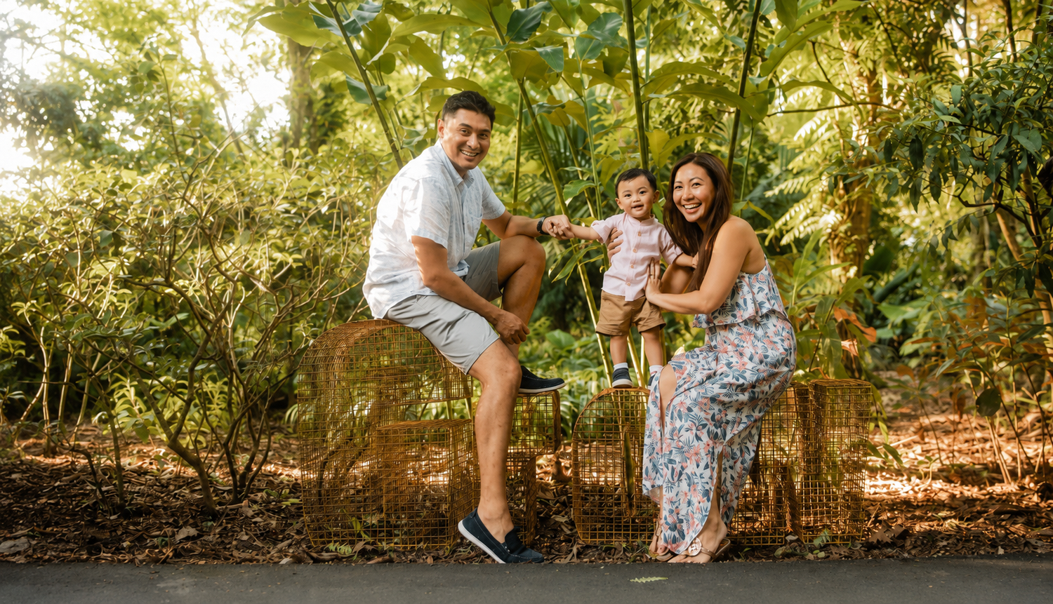 Happy family with baby on swing surrounded by lush greenery outdoors.