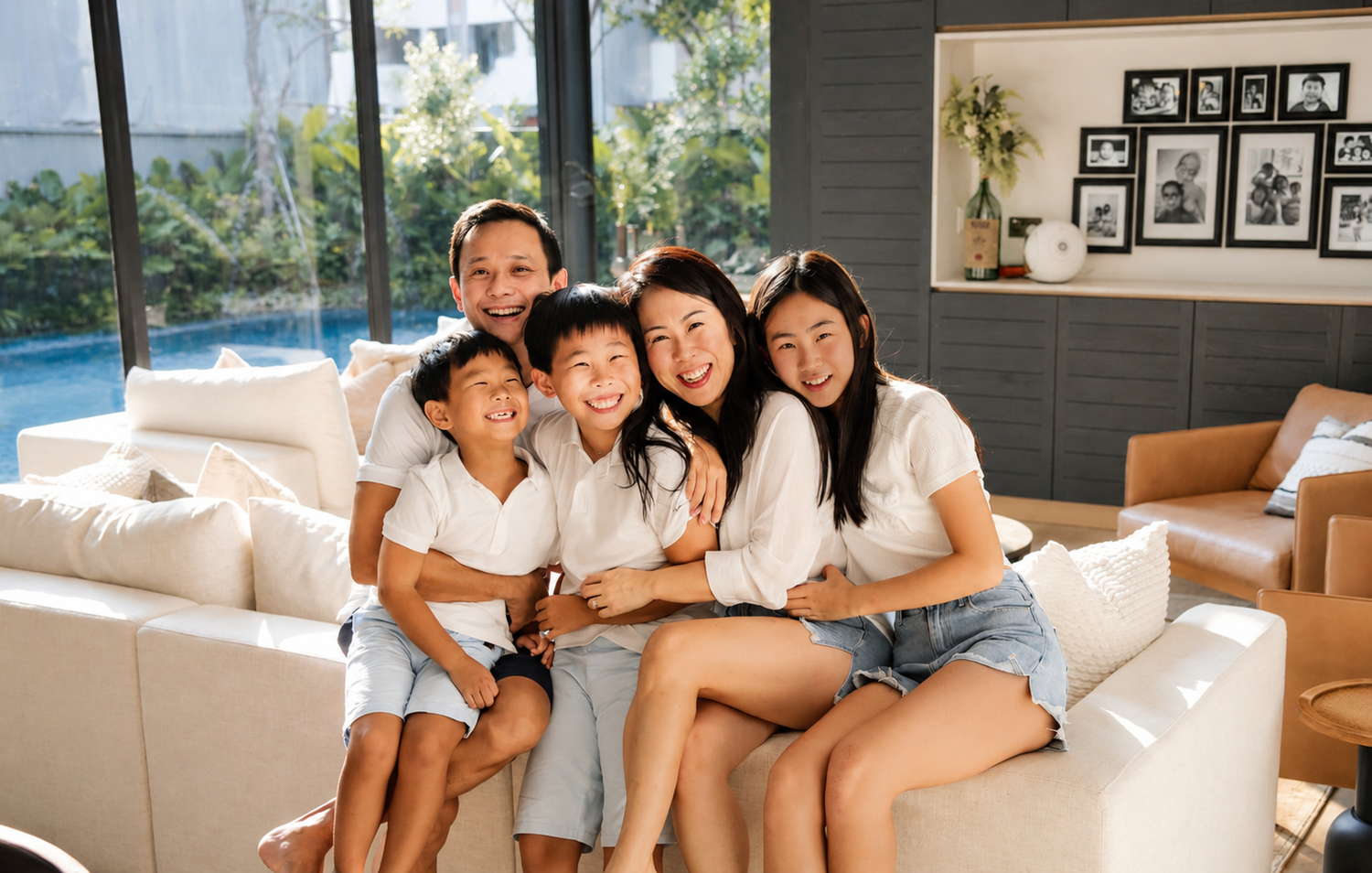 Four Asian children hugging and smiling together on a white couch in a stylish living room.